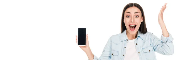 Mujer joven emocionada mostrando teléfono inteligente con pantalla en blanco aislado en blanco, plano panorámico - foto de stock
