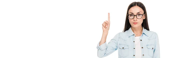 Brunette girl in glasses in denim jacket pointing with finger upwards isolated on white, panoramic shot — Stock Photo