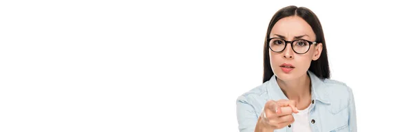 Chica morena enojada en gafas en chaqueta de mezclilla apuntando con el dedo a la cámara aislada en blanco, tiro panorámico - foto de stock