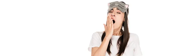 Brunette young woman in cat sleeping eye mask yawing isolated on white, panoramic shot — Stock Photo