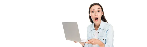 Shocked girl in denim jacket holding laptop isolated on white, panoramic shot — Stock Photo