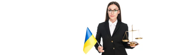 Avvocato in tuta nera con bandiera ucraina e bilancia sulla giustizia isolata su colpo bianco, panoramico — Foto stock