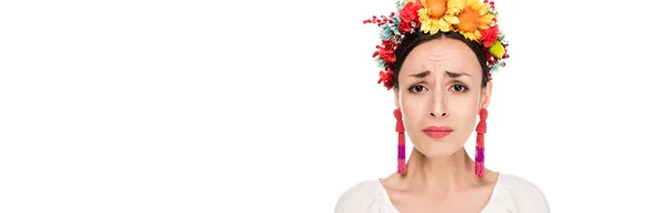 Засмучений брюнетка молода жінка в національній українській вишиванці та квітковому Вінці, ізольованих на білому, панорамному знімку — стокове фото