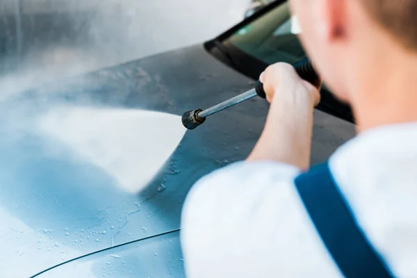 Selective focus of man washing grey auto outside — Stock Photo