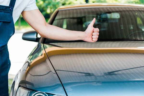 Cropped view of car washer showing thumb up near grey car — Stock Photo