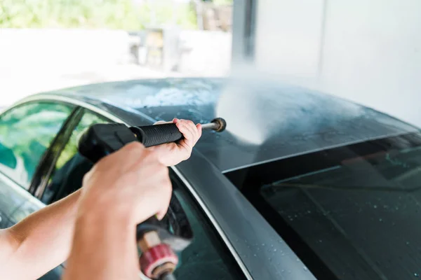 Selective focus of man washing grey modern automobile outside in car wash — Stock Photo