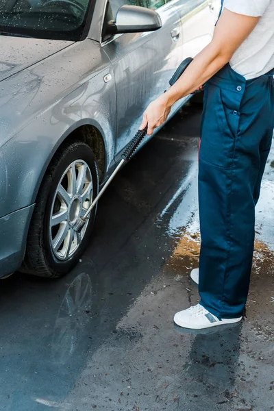Vista ritagliata dell'uomo in piedi vicino grigio moderna automobile al di fuori — Foto stock