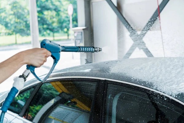 Vista ritagliata dell'uomo che tiene la rondella di pressione con schiuma vicino all'auto — Foto stock