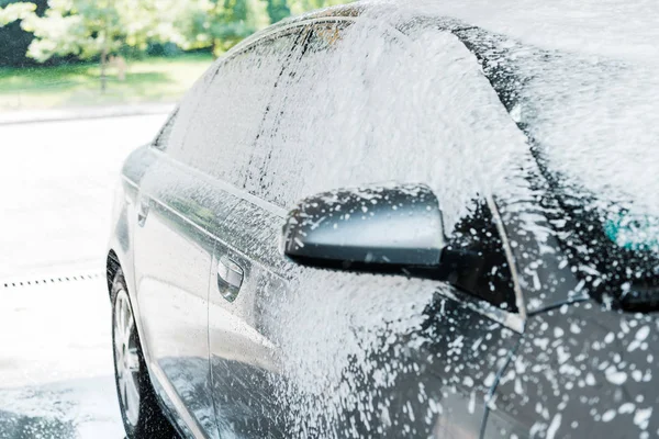 Weißer Schaum auf modernem Auto in der Waschanlage — Stockfoto