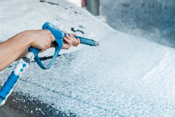 Selective focus of car cleaner holding pressure washer with foam near car — Stock Photo