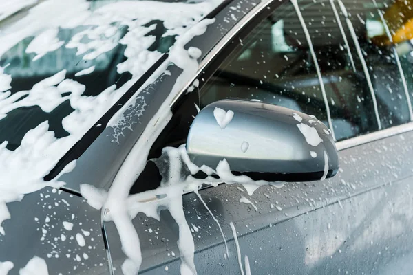 Vista recortada del espejo del coche con espuma blanca en el lavado del coche - foto de stock