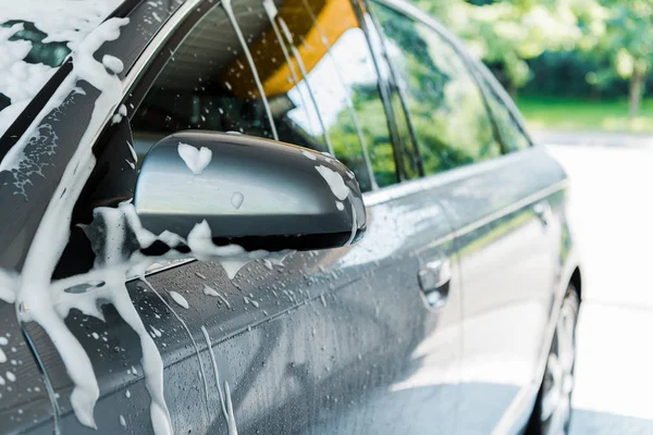 Messa a fuoco selettiva di specchio auto con schiuma bianca in autolavaggio — Foto stock