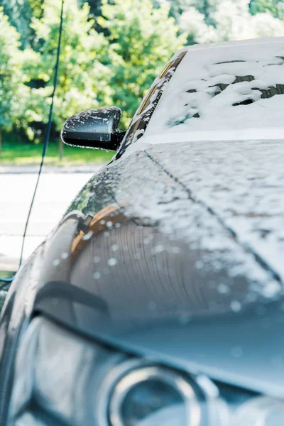 Selektiver Fokus des grauen Autos mit weißem Schaum in der Waschanlage — Stockfoto