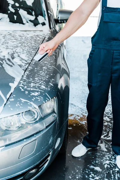 Vista recortada del hombre que sostiene la tarjeta de crédito cerca del coche con espuma - foto de stock