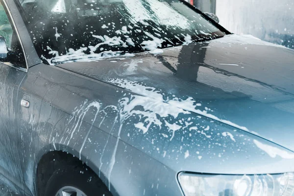 Foyer sélectif de gris auto avec mousse blanche dans le lavage de voiture — Photo de stock