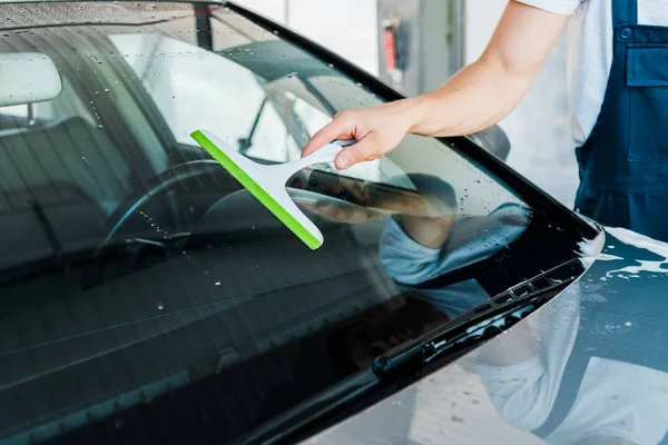 Vista recortada del limpiador de automóviles que sostiene la escobilla mientras lava la ventana del coche - foto de stock