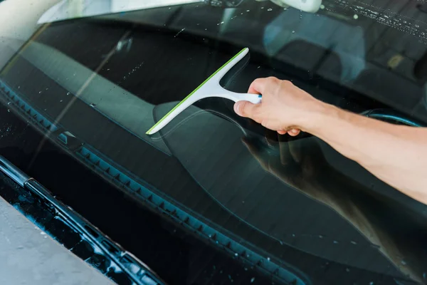 Cropped view of man holding squeegee and washing car window — Stock Photo