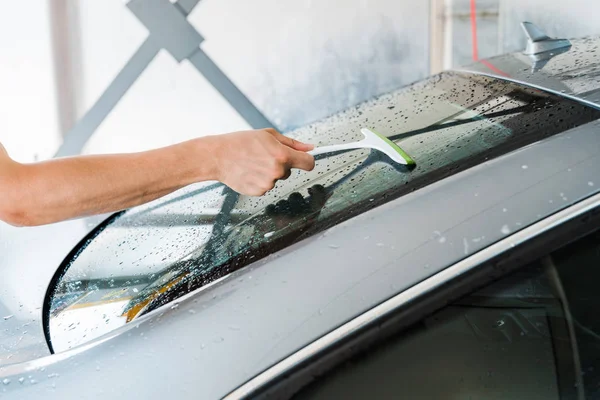 Vista cortada da máquina de lavar carro segurando rodo e limpar a janela do carro molhado — Fotografia de Stock