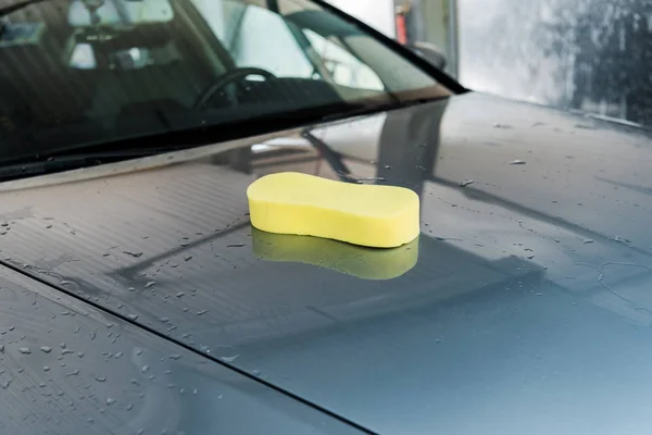 Éponge jaune sur propre et humide gris automobile — Photo de stock