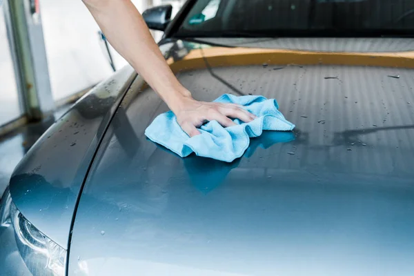 Vista cortada do homem limpando carro cinza com pano azul — Fotografia de Stock