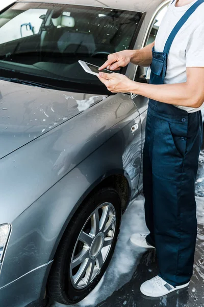 Cropped view of car cleaner pointing with finger at digital tablet with blank screen — Stock Photo