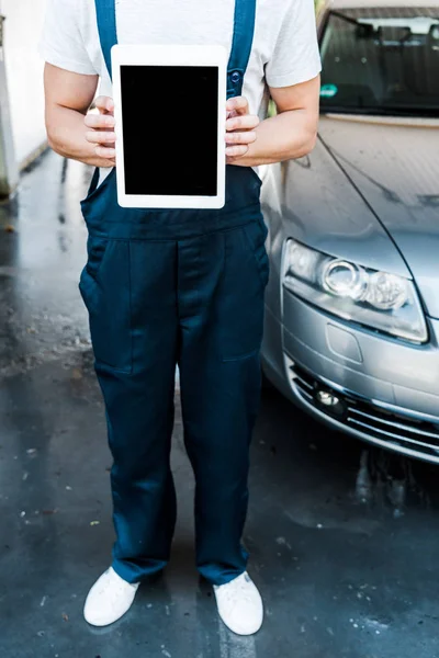 Обрізаний вид прибиральника автомобіля, що тримає цифровий планшет з порожнім екраном — стокове фото