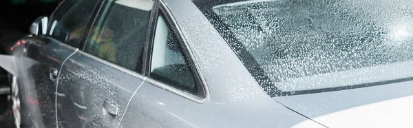 Prise de vue panoramique de gris auto avec mousse blanche dans le lavage de voiture — Photo de stock
