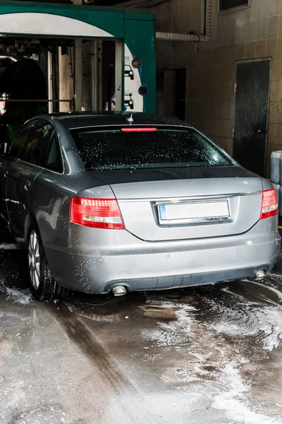 Modernes graues Fahrzeug mit weißem Schaumstoff auf dem Boden in der Waschanlage — Stockfoto