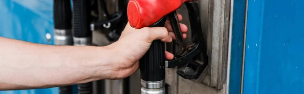 Colpo panoramico di uomo che tiene pompa di benzina rossa sul distributore di benzina — Foto stock