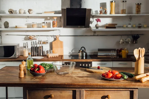 Óleo, legumes frescos e utensílios de cozinha em mesa de madeira na cozinha — Fotografia de Stock