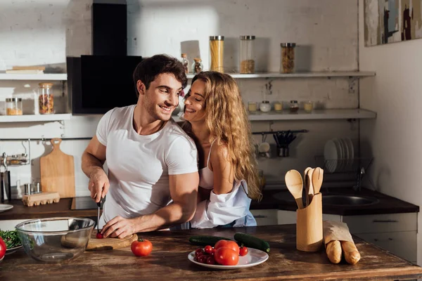 Sexy pareja sonriendo mientras cocinar juntos en cocina - foto de stock