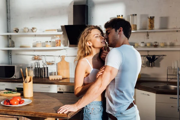 Casal sexy de pé perto da mesa com legumes na cozinha — Fotografia de Stock