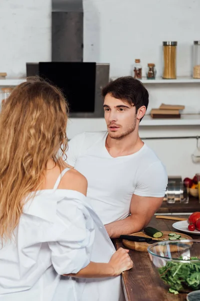 Sexy casal de pé perto de mesa de madeira na cozinha — Fotografia de Stock