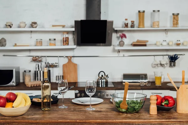 Frutas frescas, pimentão, salada, peixe e vinho na mesa na cozinha — Fotografia de Stock