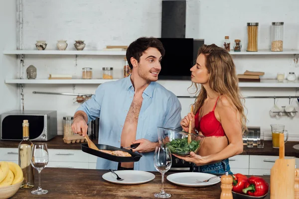 Sexy pareja cocinar juntos y sonriendo en la cocina - foto de stock