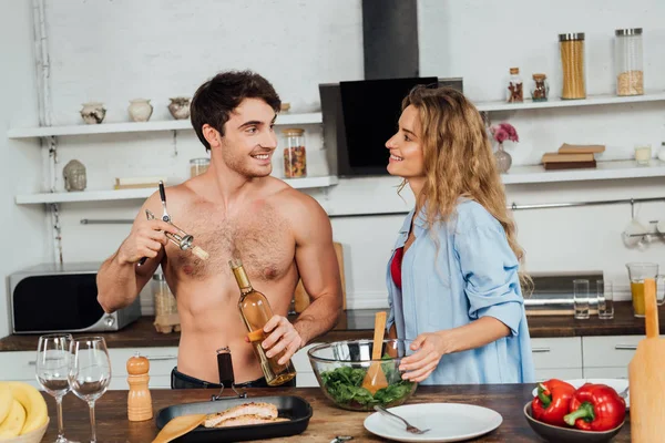 Sexy pareja sonriendo y mirándose en la cocina - foto de stock