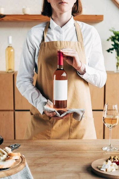 Частковий вид сомельє на фартух тримає пляшку вина — стокове фото