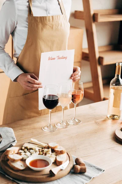 Vista recortada de sommelier en delantal celebración de documento de degustación de vinos - foto de stock