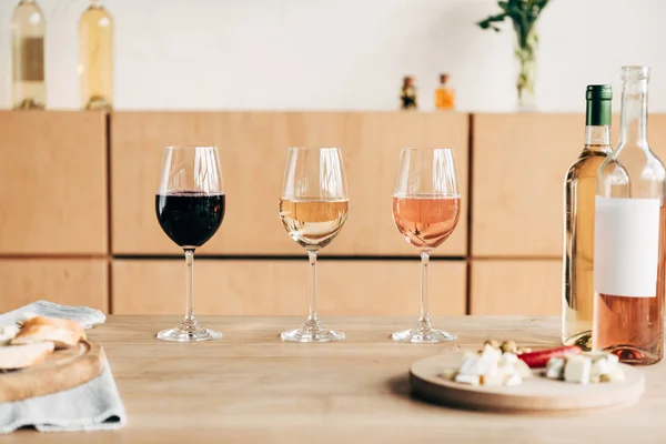 Copas de vino, botellas y comida en mesa de madera - foto de stock