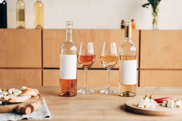 Enfoque selectivo de alimentos, copas de vino y botellas en la mesa de madera - foto de stock