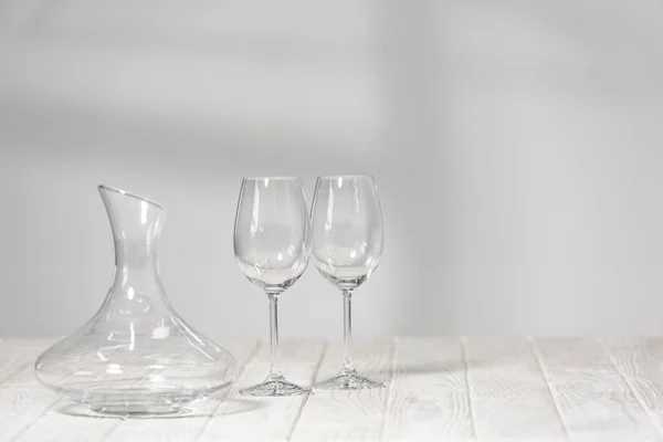 Empty wine glasses and jug on wooden surface in restaurant — Stock Photo