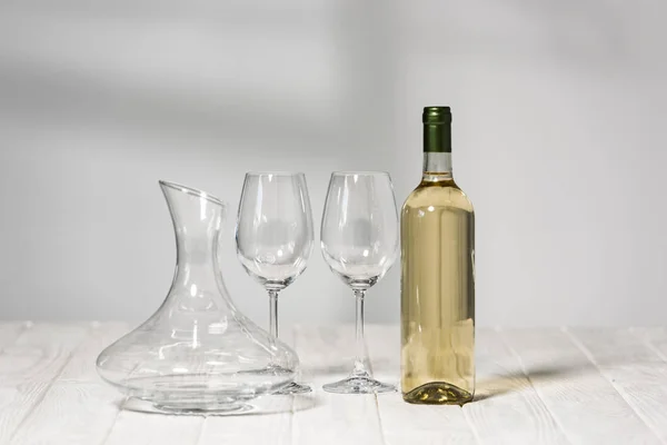 Empty wine glasses, bottle of wine and jug on wooden surface in restaurant — Stock Photo