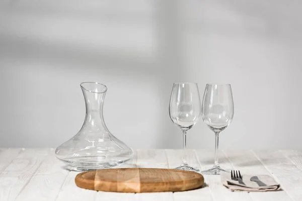 Cruche, verres à vin, couverts et planche à découper sur la surface en bois dans le restaurant — Photo de stock