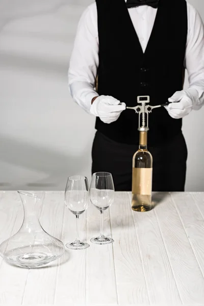 Teilansicht des Kellners in weißen Handschuhen, der eine Flasche Wein mit Korkenzieher öffnet — Stockfoto