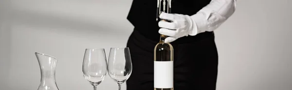 Plano panorámico de camarero en guante blanco abriendo botella de vino en restaurante - foto de stock