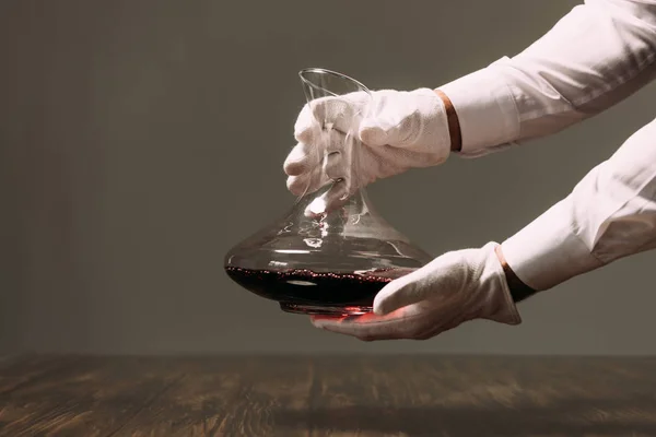 Visão parcial do garçom em luvas brancas segurando jarro de vinho no restaurante — Fotografia de Stock