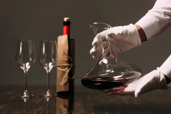 Vue partielle du serveur dans des gants blancs tenant cruche de vin au restaurant — Photo de stock