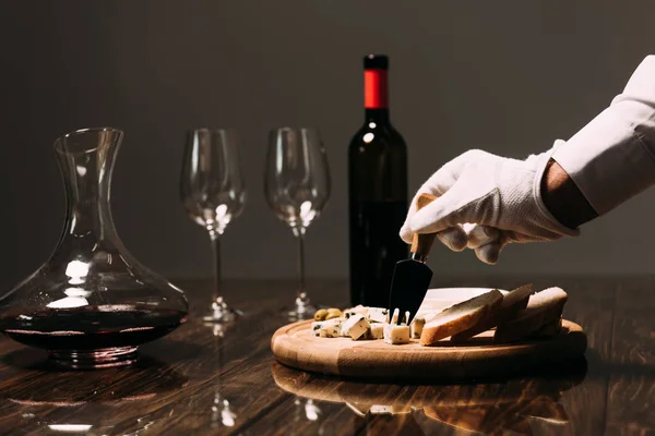 Cropped view of waiter in white glove near table with food and wine — Stock Photo