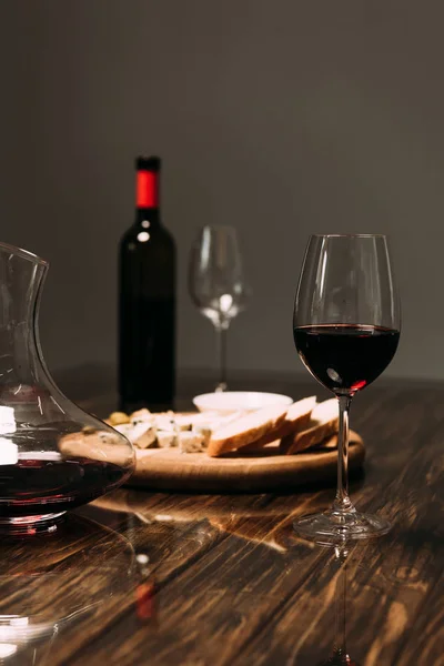 Bicchieri di vino, brocca, bottiglia di vino e cibo sul tavolo di legno nel ristorante — Foto stock