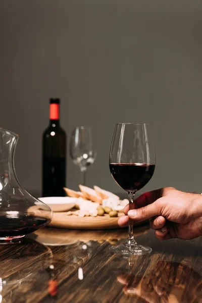 Vista recortada del hombre sosteniendo copa de vino en la mesa en el restaurante - foto de stock